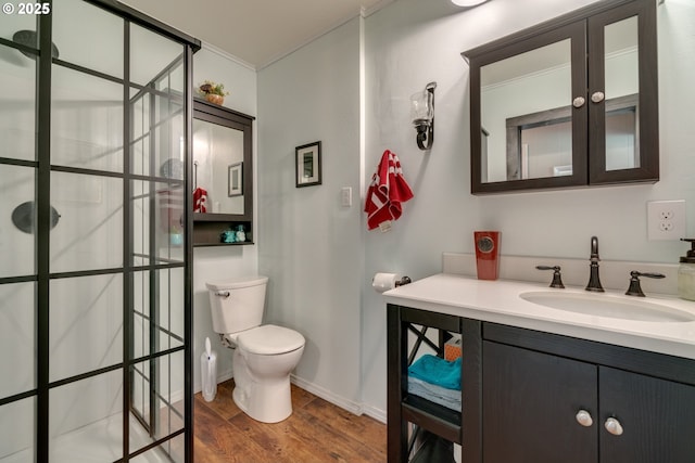 bathroom featuring baseboards, toilet, wood finished floors, vanity, and a shower