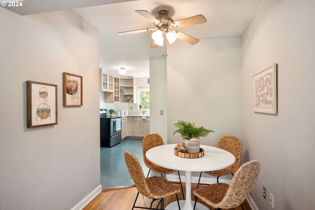 dining area with ceiling fan, sink, and light hardwood / wood-style flooring