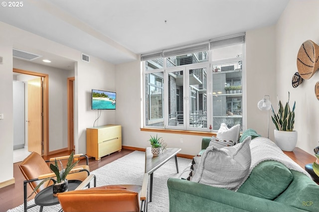 living room with visible vents, baseboards, and wood finished floors