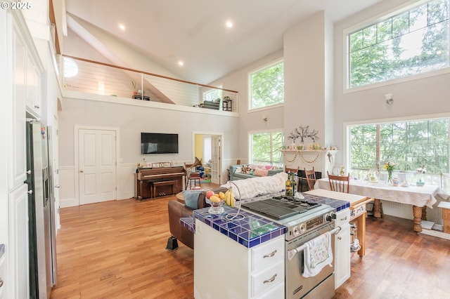 895 Pine Forest Dr, Eugene, OR 97405 - kitchen with tile counters, high end stove, a towering ceiling, white cabinets, and light wood-style floors