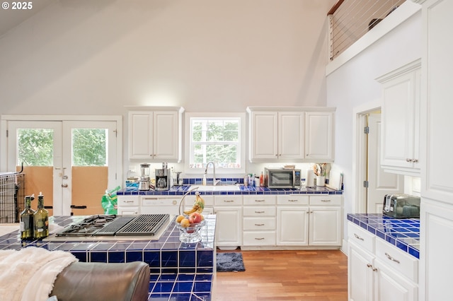 895 Pine Forest Dr, Eugene, OR 97405 - kitchen with tile countertops, a high ceiling, stainless steel appliances, light wood-type flooring, and white cabinets
