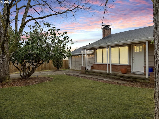 view of yard with driveway, an attached garage, and fence