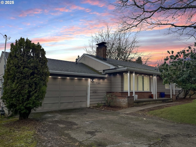 view of front of house with brick siding, a shingled roof, aphalt driveway, a chimney, and an attached garage