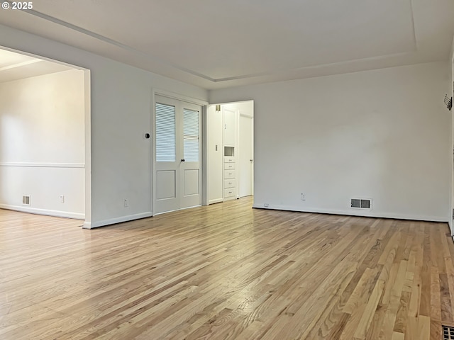 spare room with light wood-style flooring, baseboards, and visible vents