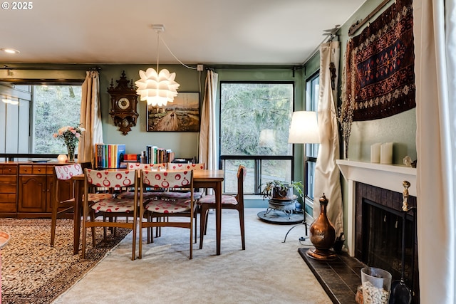 dining area featuring a tile fireplace, carpet, and plenty of natural light