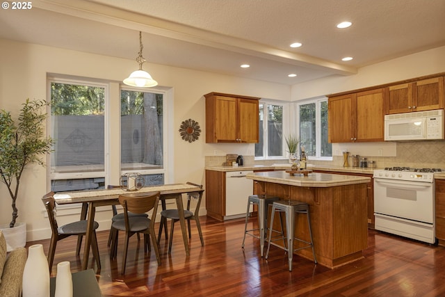 kitchen with light countertops, recessed lighting, dark wood-type flooring, white appliances, and brown cabinetry