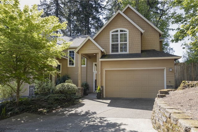 traditional-style home with fence, a shingled roof, driveway, and an attached garage