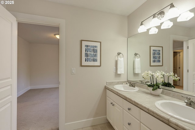 bathroom with baseboards, double vanity, and a sink
