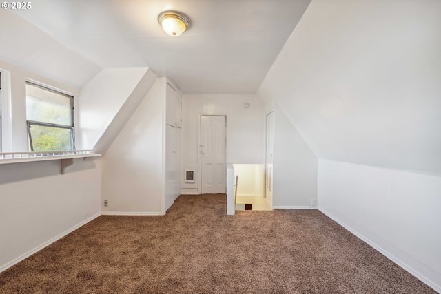 additional living space featuring vaulted ceiling and carpet flooring