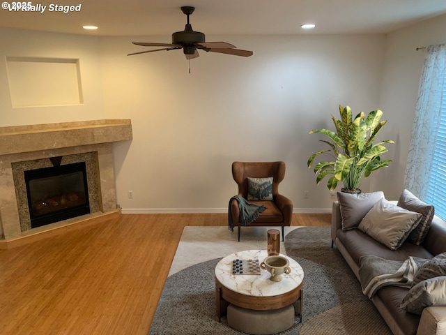 living room featuring ceiling fan, hardwood / wood-style floors, and a fireplace