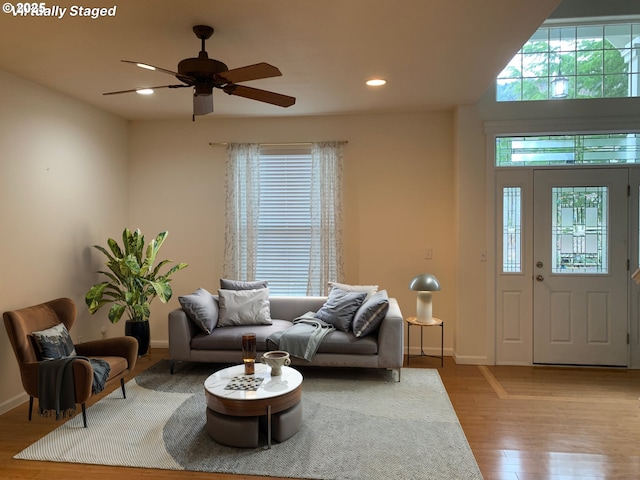 living room featuring ceiling fan, light wood-type flooring, and plenty of natural light