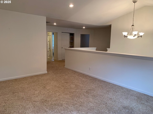 carpeted empty room featuring vaulted ceiling and an inviting chandelier