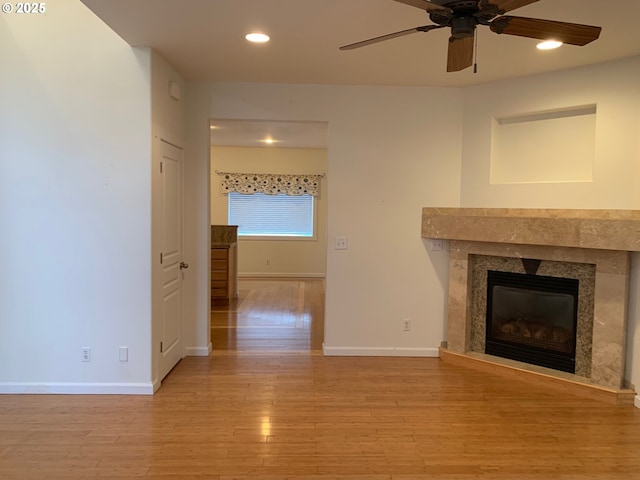 unfurnished living room featuring ceiling fan, light wood-type flooring, and a fireplace