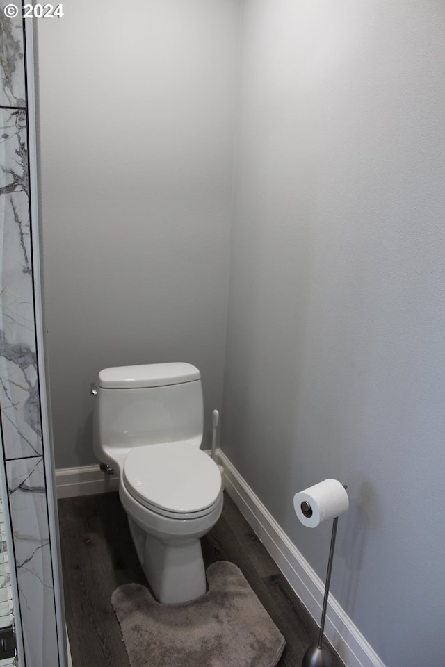 bathroom with toilet, wood finished floors, and baseboards