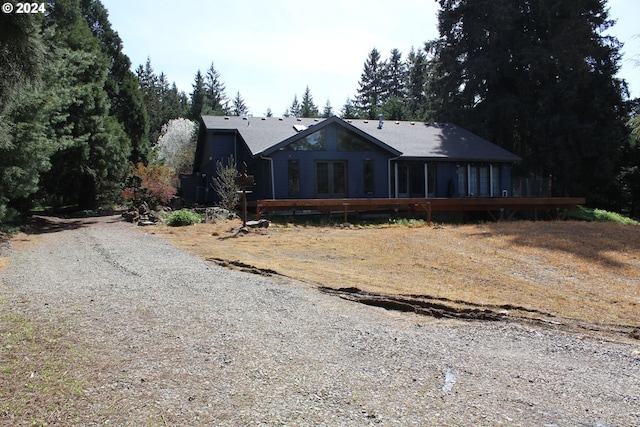 view of front of property featuring french doors, gravel driveway, and a wooden deck