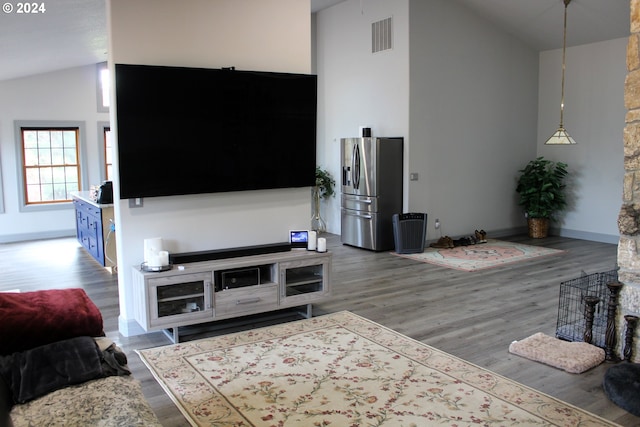 living room with visible vents, baseboards, high vaulted ceiling, and wood finished floors