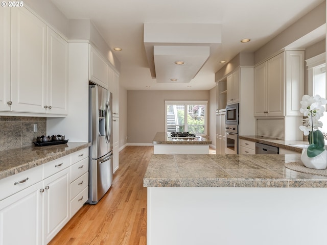 6903 SE Riverside Dr Unit 20, Vancouver, WA 98664 - kitchen with stainless steel appliances, tile counters, light wood finished floors, tasteful backsplash, and white cabinetry