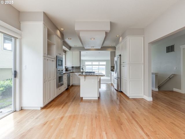 6903 SE Riverside Dr Unit 20, Vancouver, WA 98664 - kitchen with stainless steel appliances, a breakfast bar, light wood-type flooring, white cabinetry, and open shelves