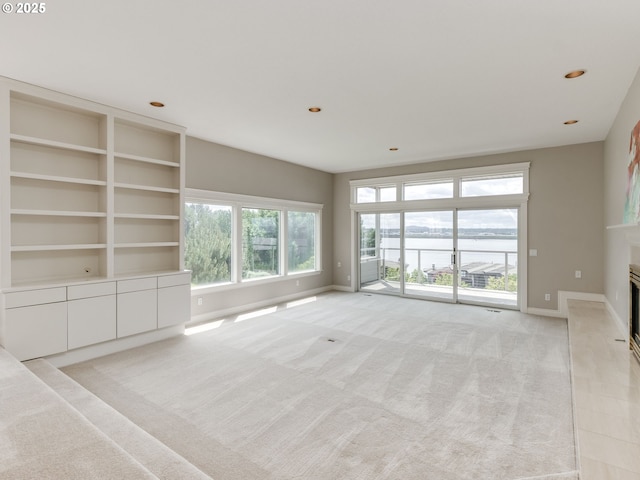 6903 SE Riverside Dr Unit 20, Vancouver, WA 98664 - unfurnished living room featuring a water view, light carpet, baseboards, a glass covered fireplace, and recessed lighting