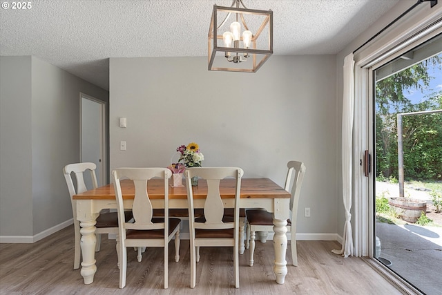 1220 Baker St, Baker City, OR 97814 - dining space with light wood-style flooring, a textured ceiling, a chandelier, and baseboards