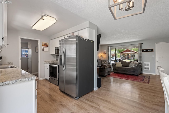 1220 Baker St, Baker City, OR 97814 - kitchen with stainless steel appliances, light countertops, white cabinetry, light wood-type flooring, and open floor plan