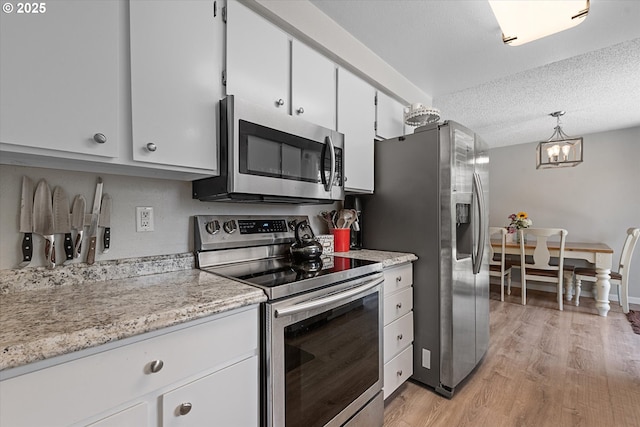 1220 Baker St, Baker City, OR 97814 - kitchen featuring appliances with stainless steel finishes, light wood-style floors, white cabinets, a chandelier, and a textured ceiling