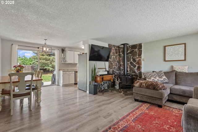 1220 Baker St, Baker City, OR 97814 - living area with a textured ceiling, a wood stove, light wood finished floors, and a chandelier