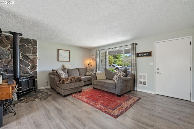 1220 Baker St, Baker City, OR 97814 - living room featuring a wood stove, wood finished floors, a textured ceiling, and baseboards