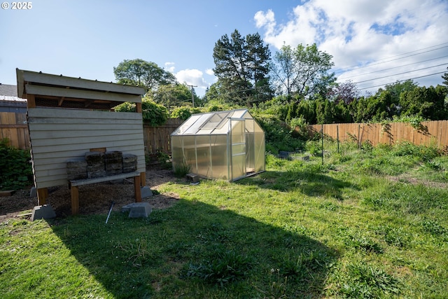 view of yard featuring a greenhouse and an outbuilding