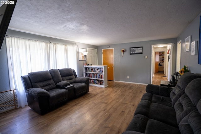 living room with a textured ceiling, hardwood / wood-style flooring, and baseboards