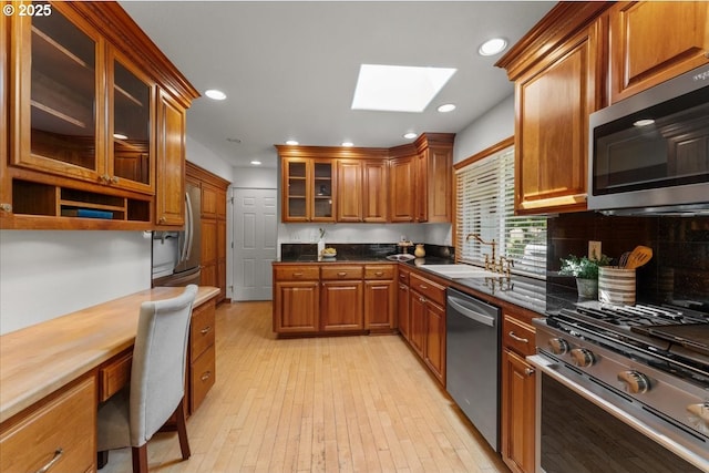 9150 SW Salmon St, Portland, OR 97225 - kitchen with appliances with stainless steel finishes, a skylight, brown cabinetry, recessed lighting, and light wood finished floors