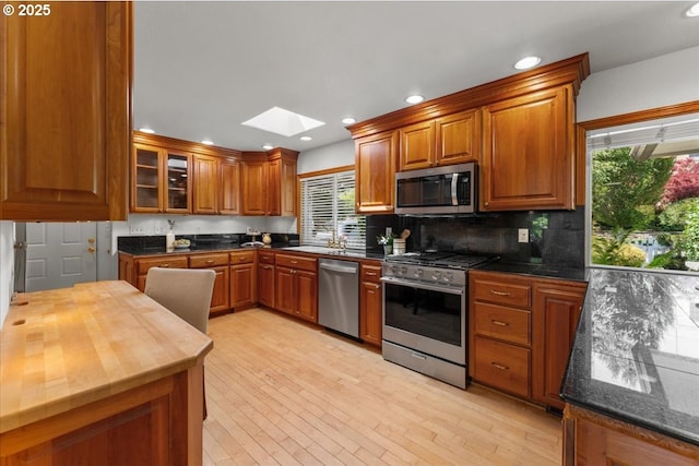 9150 SW Salmon St, Portland, OR 97225 - kitchen featuring stainless steel appliances, a skylight, brown cabinetry, healthy amount of natural light, and recessed lighting