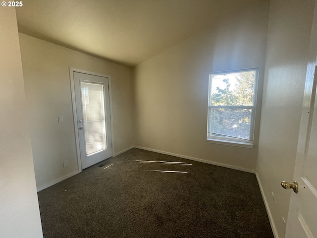 spare room with vaulted ceiling and dark carpet