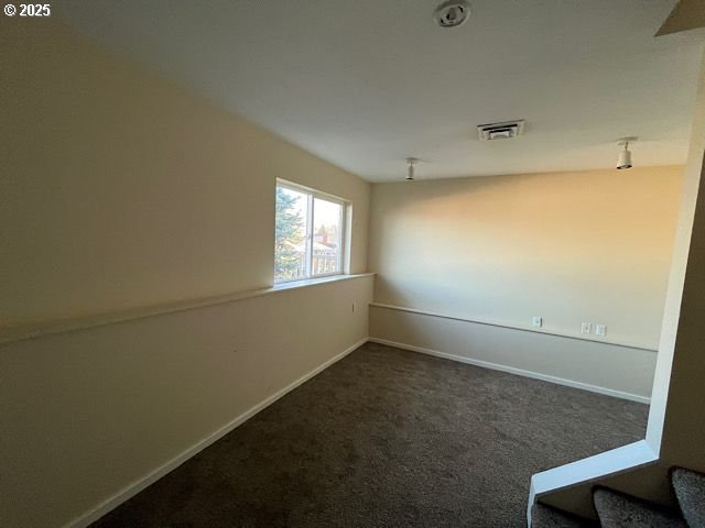 spare room featuring dark colored carpet