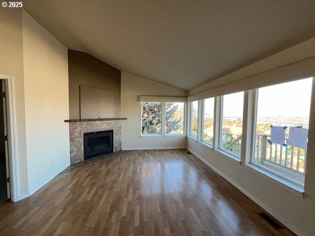 unfurnished living room featuring lofted ceiling and wood-type flooring