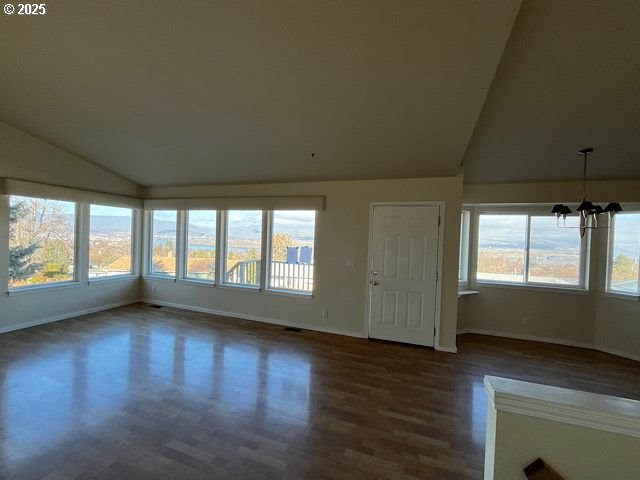 unfurnished living room with lofted ceiling, dark wood-type flooring, and a chandelier