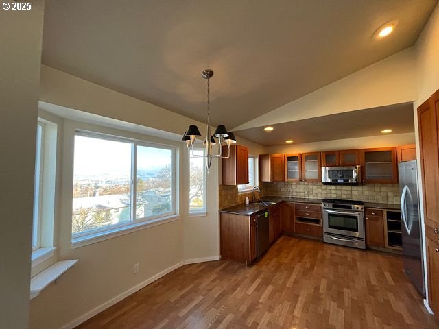 kitchen featuring pendant lighting, sink, lofted ceiling, appliances with stainless steel finishes, and backsplash