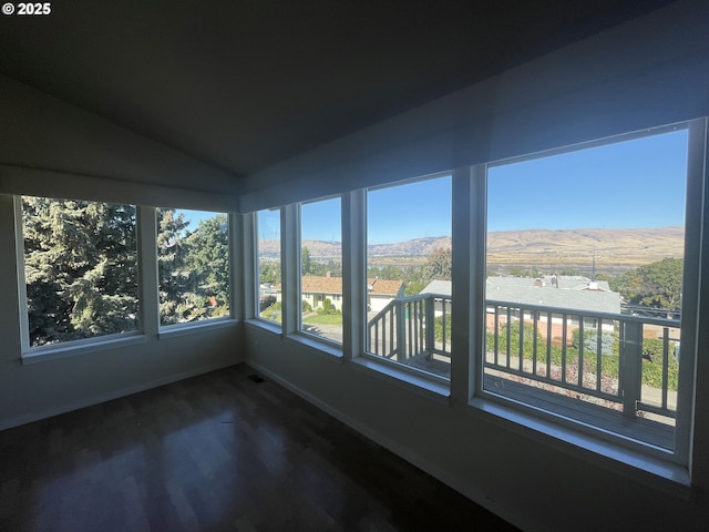 unfurnished sunroom with vaulted ceiling, a mountain view, and a healthy amount of sunlight