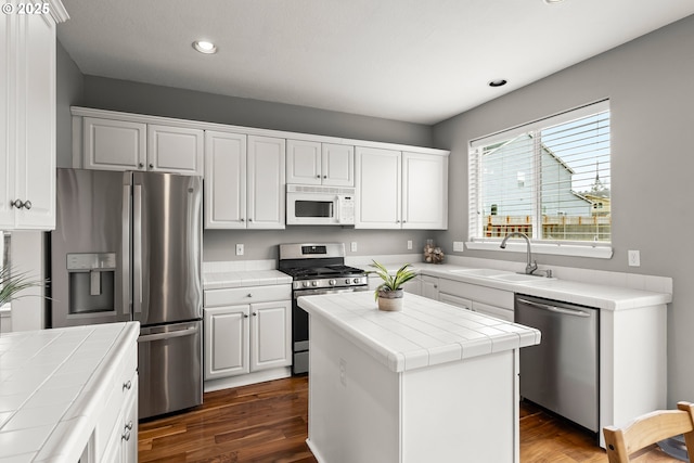 kitchen with stainless steel appliances, tile countertops, a center island, and sink