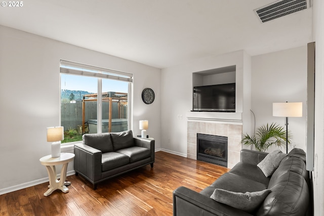 living room featuring a tile fireplace and hardwood / wood-style floors