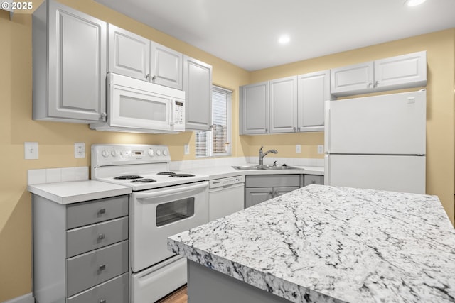 kitchen with white appliances, light countertops, gray cabinetry, a sink, and recessed lighting