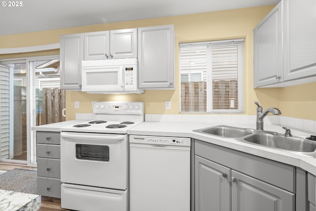 kitchen featuring white appliances, light countertops, a sink, and gray cabinetry