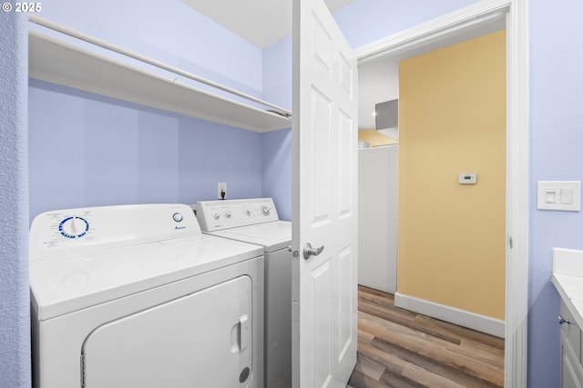 laundry area featuring laundry area, washing machine and dryer, baseboards, and wood finished floors