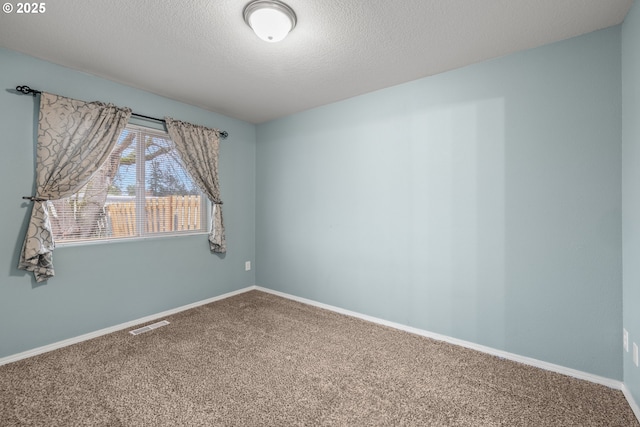 carpeted spare room featuring visible vents, baseboards, and a textured ceiling