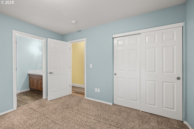 unfurnished bedroom with carpet, a closet, a textured ceiling, and baseboards