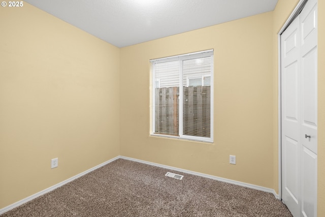 carpeted spare room featuring baseboards and visible vents