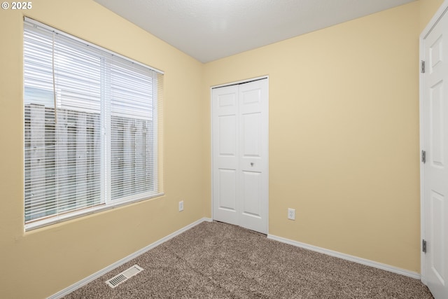 unfurnished bedroom featuring carpet floors, a closet, visible vents, and baseboards