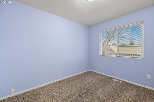 carpeted empty room featuring visible vents, baseboards, and a textured ceiling