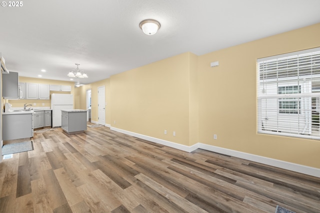 unfurnished living room featuring baseboards, recessed lighting, light wood-style flooring, and an inviting chandelier