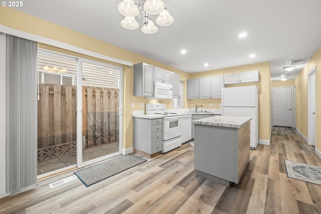 kitchen featuring white appliances, visible vents, a sink, and light wood finished floors